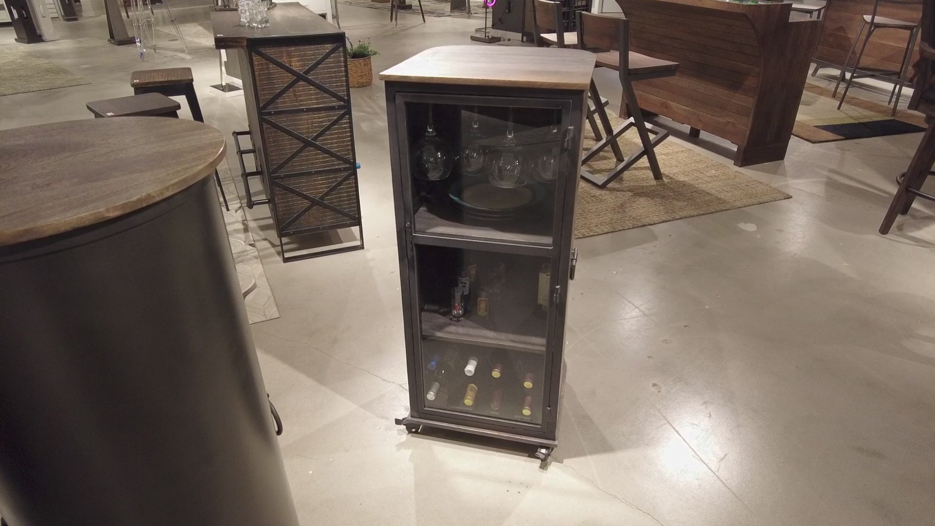 A modern glass-fronted display cabinet on wheels, showcasing various bottles inside.