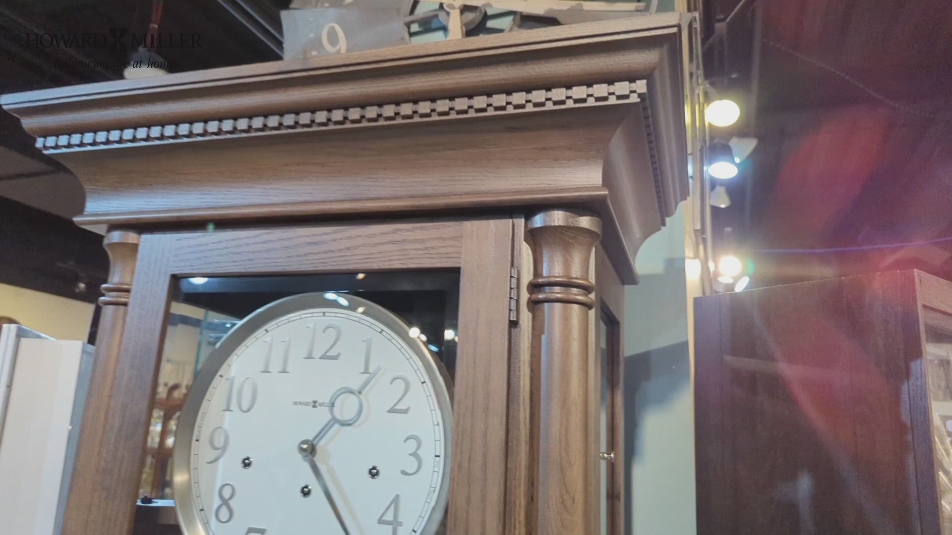 Close-up of a wooden grandfather clock with a circular clock face and decorative top