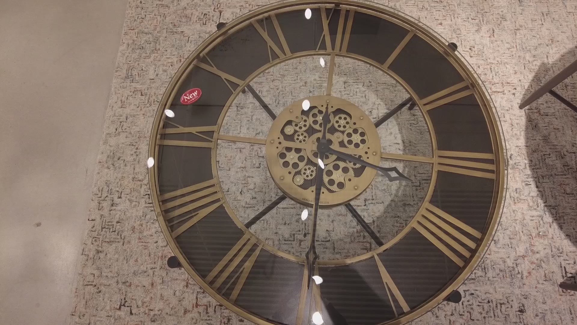 A large decorative wall clock with Roman numerals and a vintage design, showing the gears of the clock face moving.