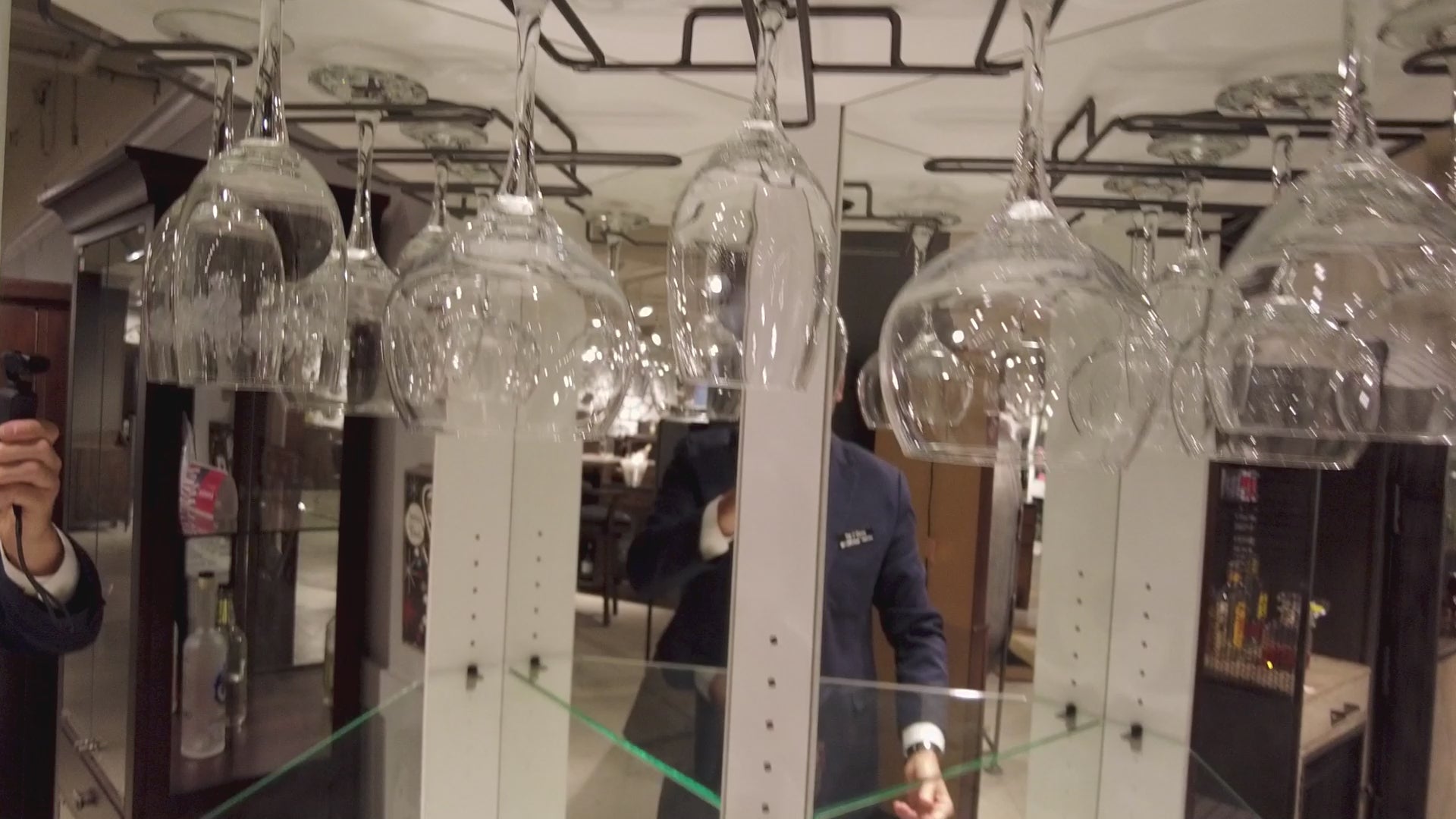 Reflection of glassware and a person in a display.