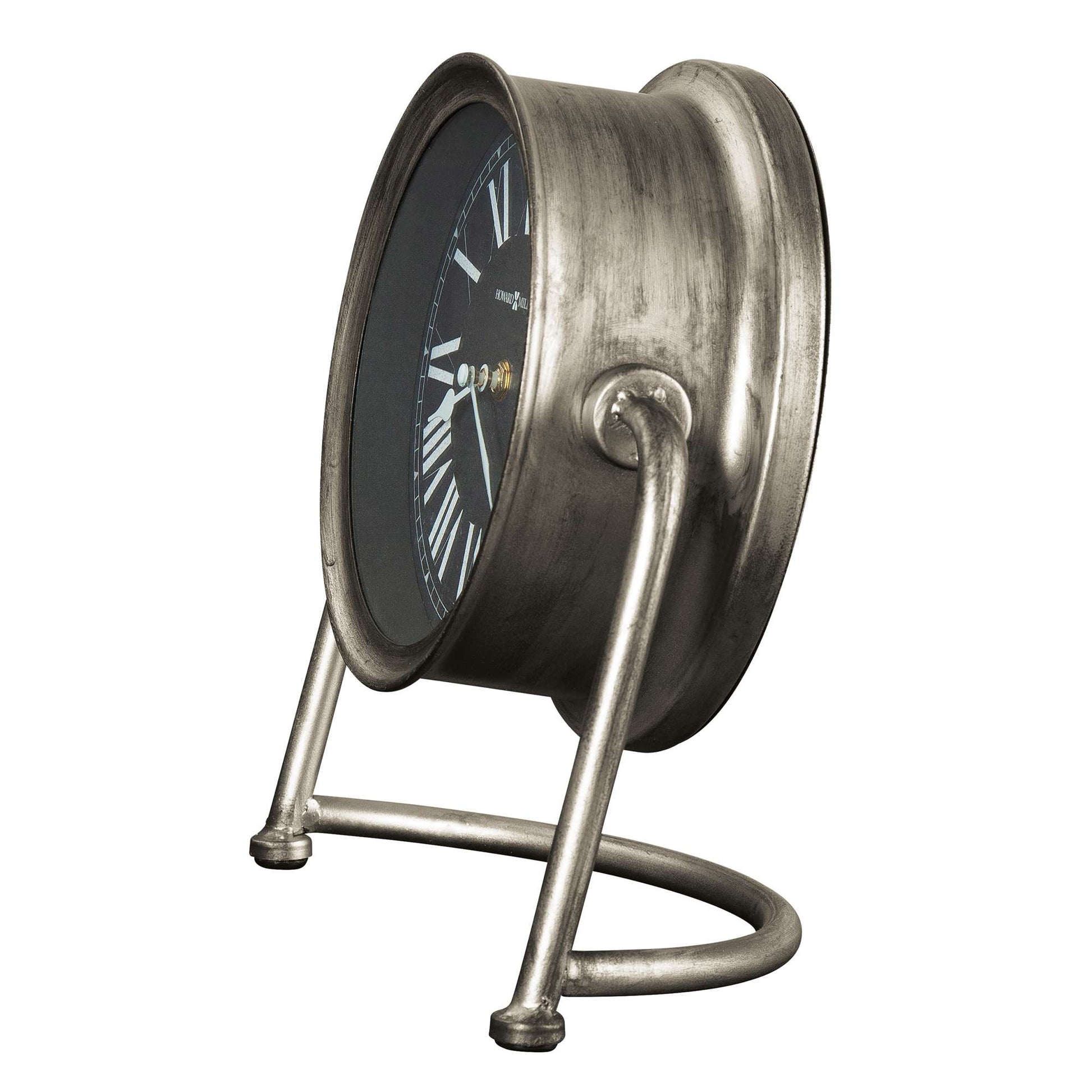 A vintage alarm clock with a round metallic body and stand, featuring a black face and white hour markings.