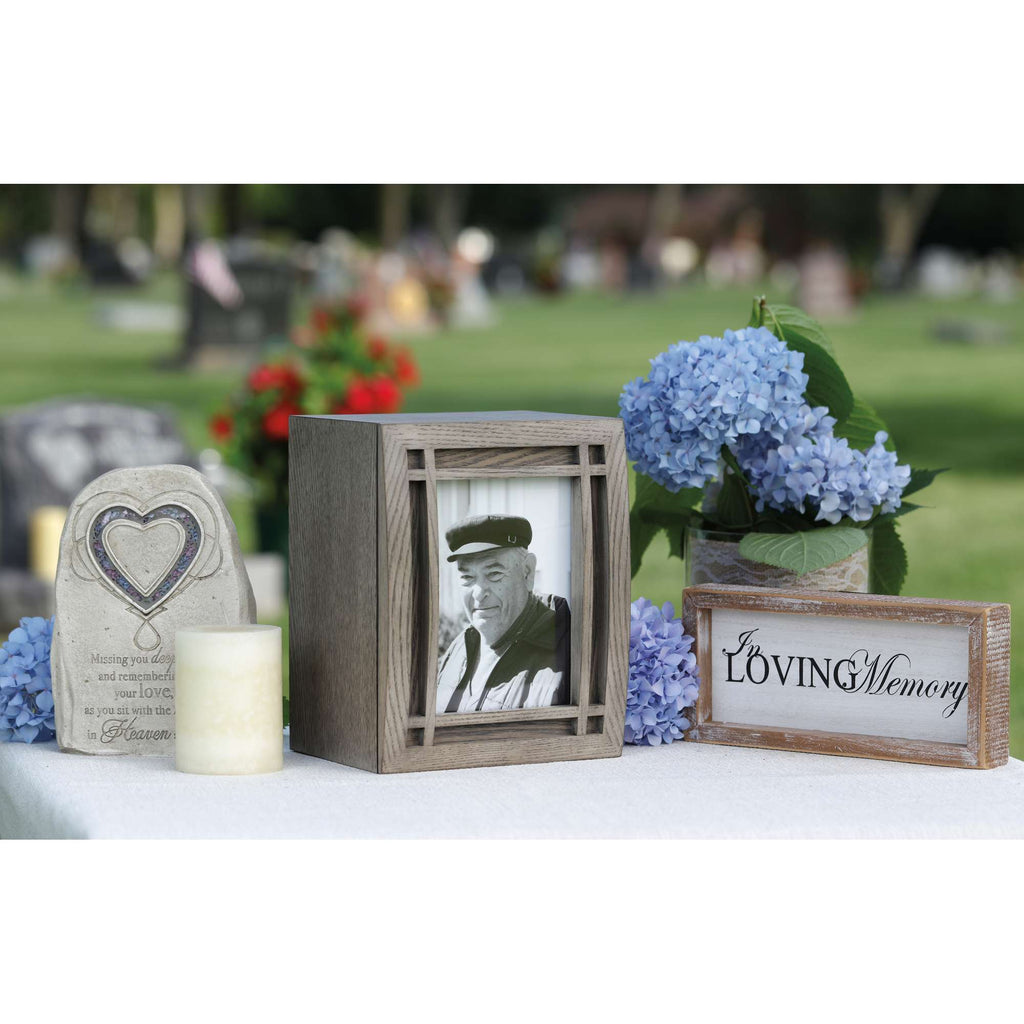 A memorial display featuring a framed photo, flowers, and heartfelt messages.